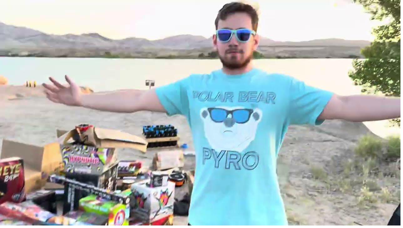 Polar Bear Pyro at a Nevada lake shoot site, wearing his branded POLAR BEAR PYRO tee, fireworks boxes visible alongside